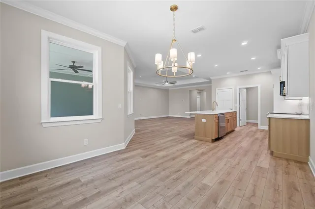 a view of a room with wooden floor kitchen chandelier and windows
