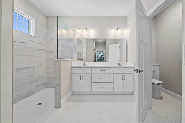 a bathroom with a granite countertop sink a toilet and shower