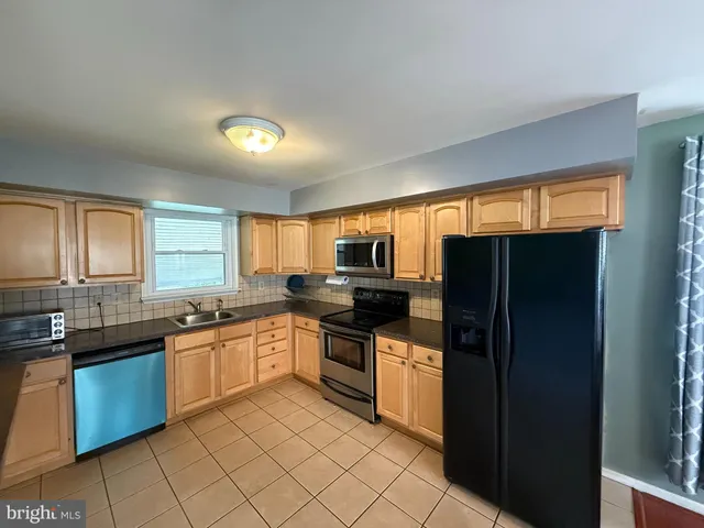 a kitchen with stainless steel appliances granite countertop refrigerator a sink a stove a microwave a counter space and cabinets