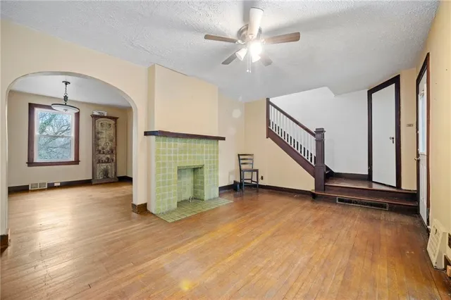 an empty room with wooden floor staircase and windows