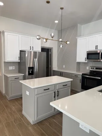 a kitchen that has a lot of white cabinets and stainless steel appliances