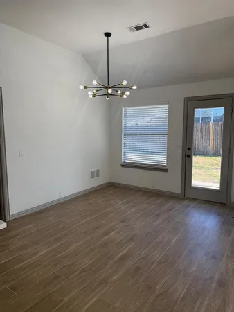 a view of an empty room with a window and wooden floor