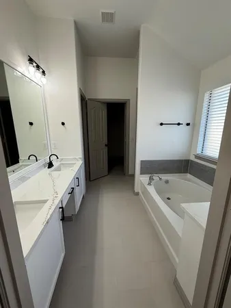 a bathroom with a tub a sink and mirror