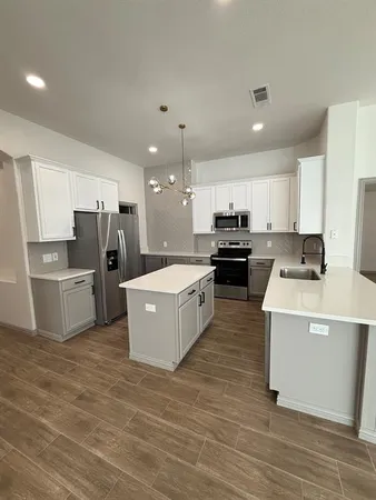 a kitchen with refrigerator a microwave a stove and white cabinets with wooden floor