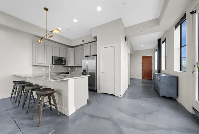 a kitchen with stainless steel appliances granite countertop a table chairs sink and cabinets