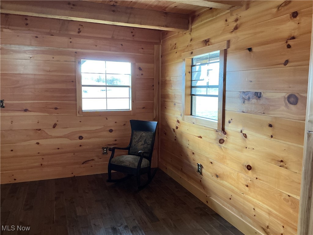 10550 Symmes Creek Road Adamsville, OH 43802 - Photo 11 of 21 Unfurnished room featuring wooden walls, dark wood-style floors, and a wooden ceiling with exposed beams