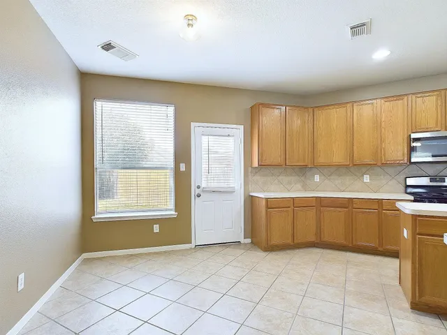 a large kitchen with granite countertop a sink window and cabinets