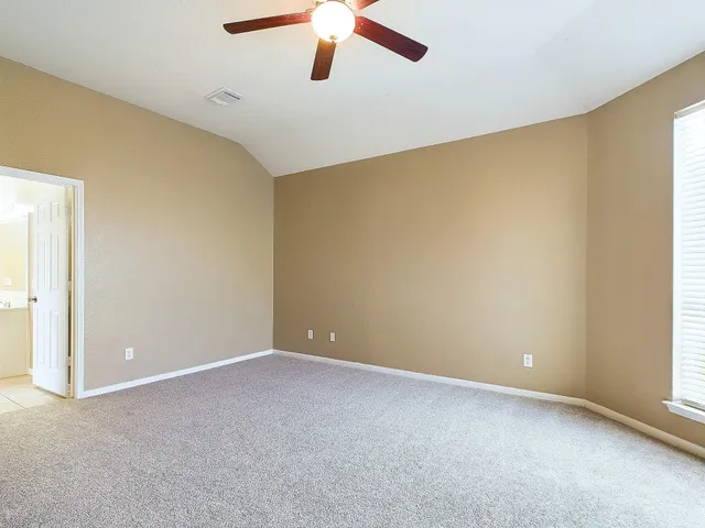 an empty room with a window and a ceiling fan