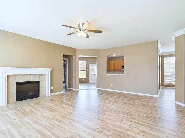 a view of an empty room with window and wooden floor