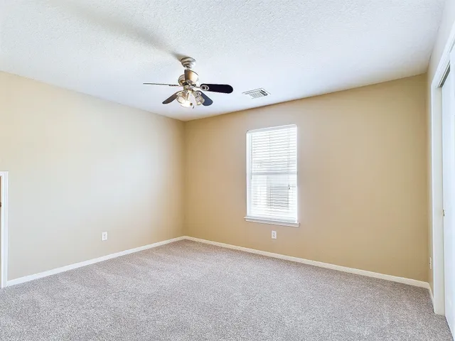 an empty room with windows and chandelier fan