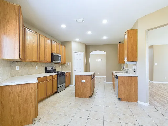 a large kitchen with stainless steel appliances lots of counter space and wooden cabinets