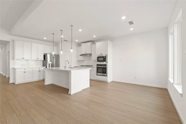 a large kitchen with kitchen island a sink a stove a refrigerator and white cabinets