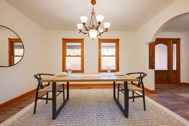 a large kitchen with stainless steel appliances a stove a sink a dining table and chairs with wooden floor