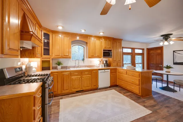 a large kitchen with stainless steel appliances granite countertop a stove a sink and a microwave