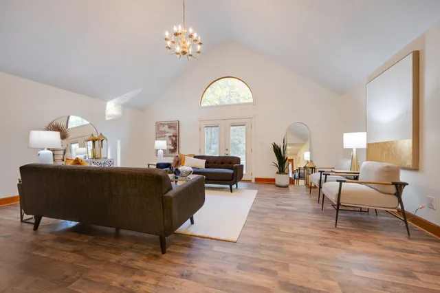 a living room with furniture chandelier and a mirror