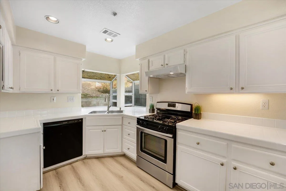 9704 Avenida Ricardo Spring Valley, CA 91977 - Photo 13 of 52 a kitchen with white cabinets and appliances