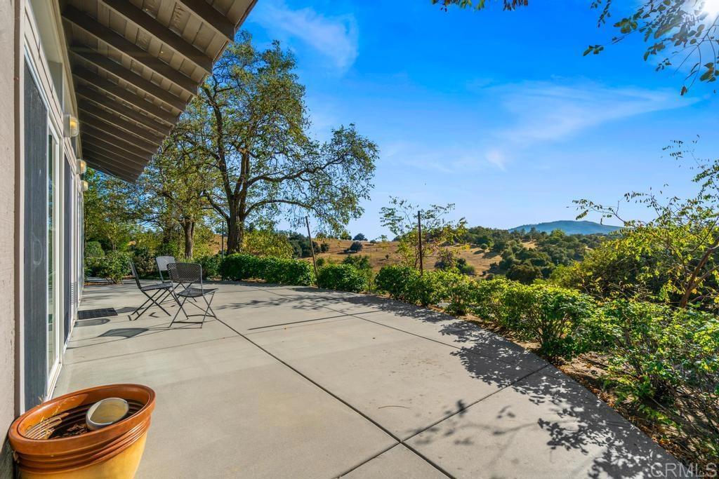 25443 Mesa Grande Road Santa Ysabel, CA 92070 - Photo 56 of 68 a backyard of a house with table and chairs under an umbrella