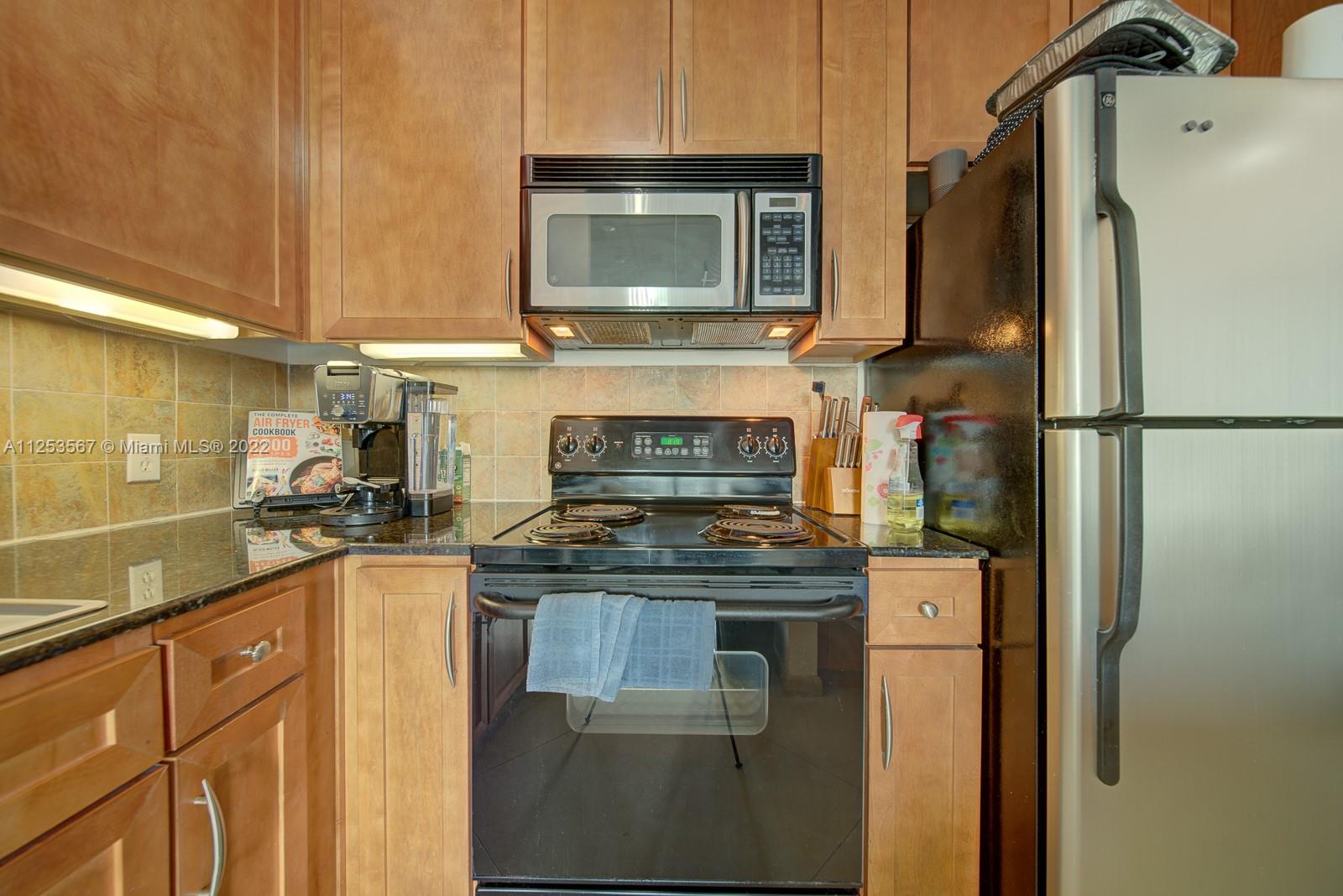 2001 Biscayne Boulevard, Unit 3401 Miami, FL 33137 - Photo 10 of 23 a kitchen with granite countertop a refrigerator stove and microwave