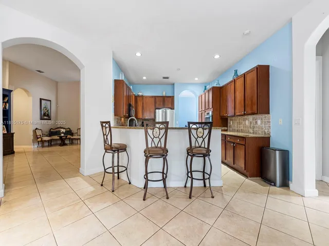 a kitchen with stainless steel appliances kitchen island granite countertop a refrigerator and cabinets
