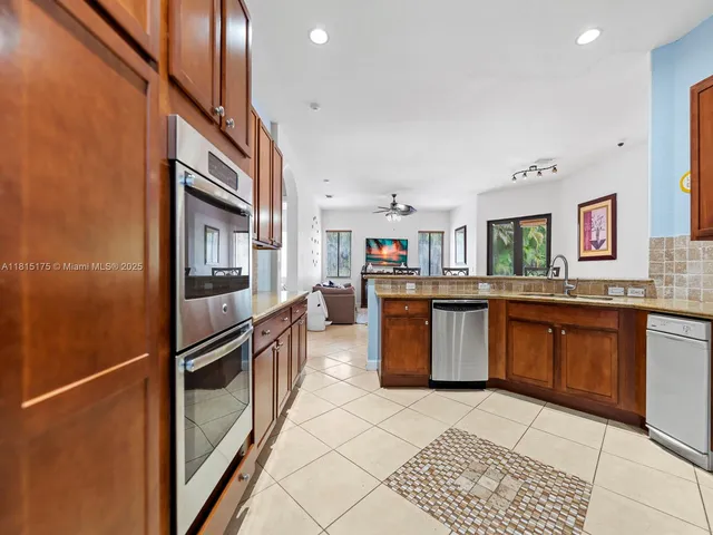 a kitchen with stainless steel appliances granite countertop a refrigerator a stove and a sink