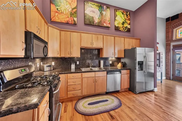 a kitchen with stainless steel appliances granite countertop a stove a sink and a refrigerator