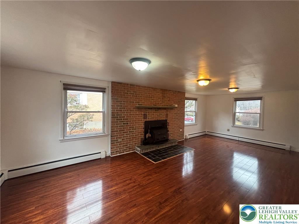 257 East 2nd Street Wind Gap, PA 18091 - Photo 6 of 14 an empty room with wooden floor fireplace and windows