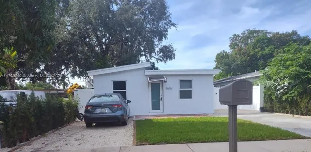 a view of a yard in front of a house with large trees and plants