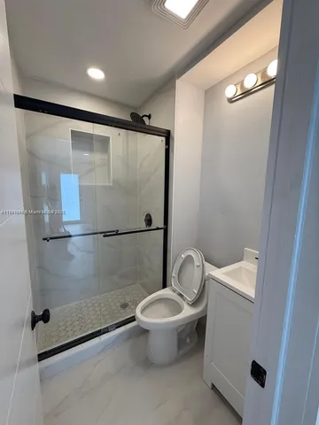 a bathroom with a granite countertop toilet and a shower
