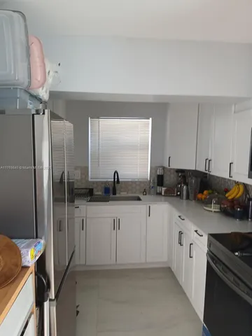 a kitchen with white cabinets and appliances