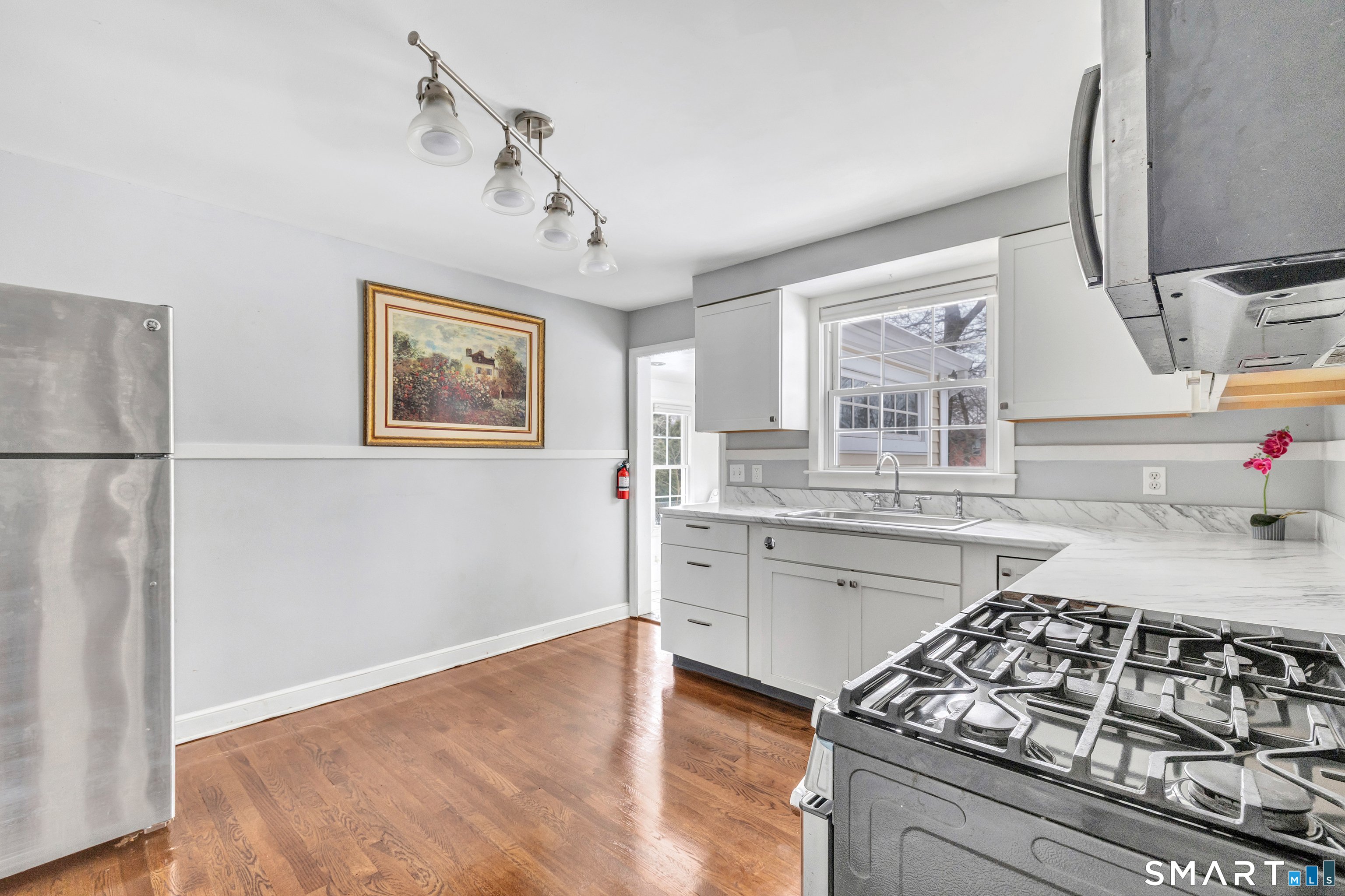 115 Spring Street Stratford, CT 06614 - Photo 16 of 26 a kitchen with stainless steel appliances granite countertop a stove a sink dishwasher and white cabinets with wooden floor