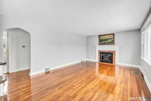 a view of empty room with wooden floor and fireplace