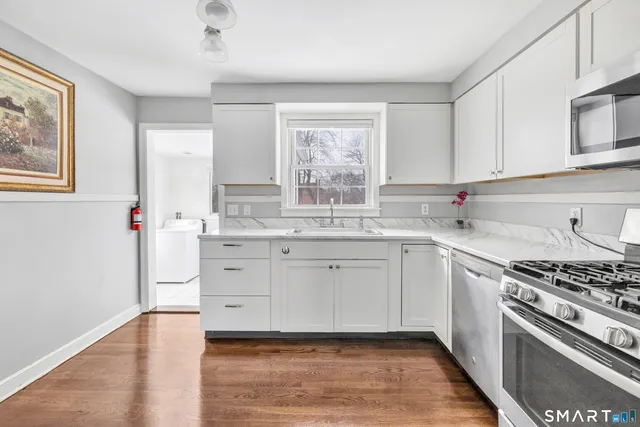 a kitchen with granite countertop a stove a sink and white cabinets