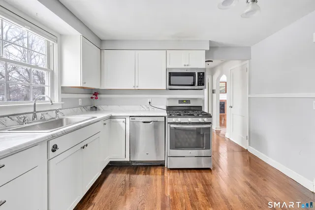 a kitchen with stainless steel appliances a sink cabinets and a window