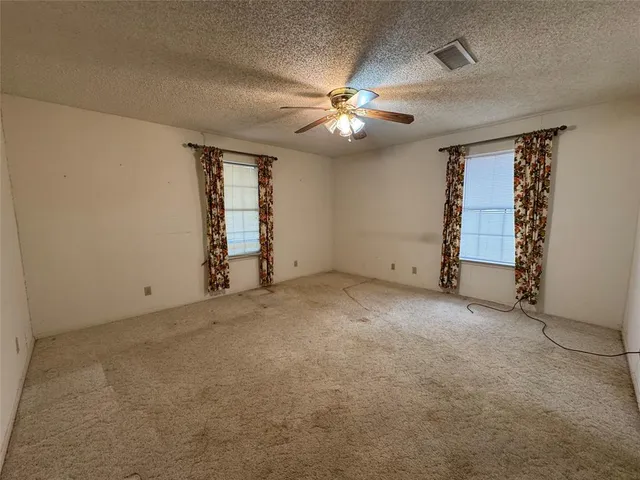 an empty room with windows and fan