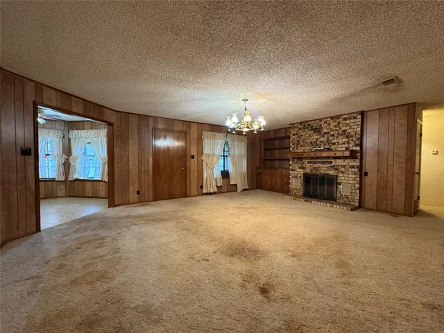 an empty room with fireplace and chandelier