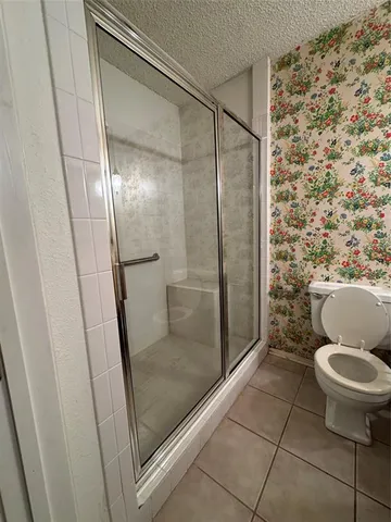 a bathroom with a granite countertop toilet and a shower