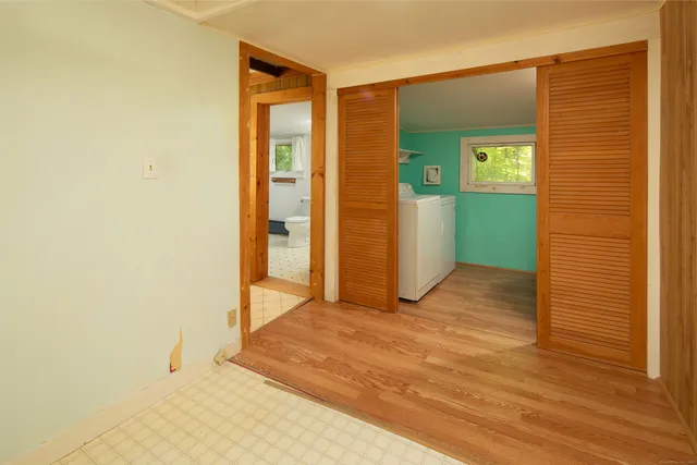 a view of an empty room with closet and a bathroom