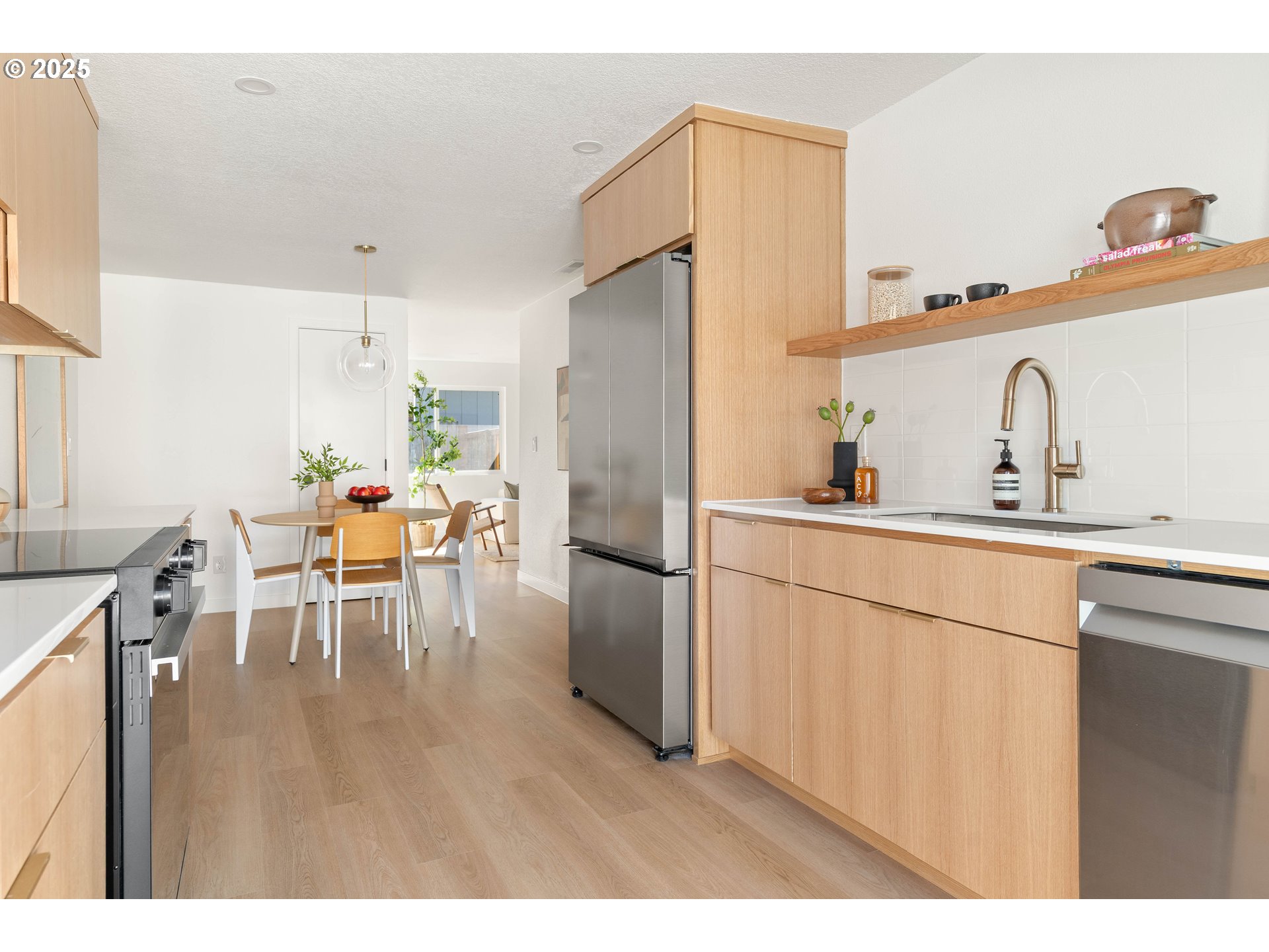 10904 Southwest 62nd Place Portland, OR 97219 - Photo 11 of 27 a kitchen with a refrigerator a sink dishwasher a dining table and chairs with wooden floor