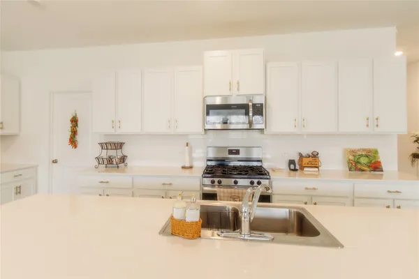 a kitchen with stainless steel appliances granite countertop a sink a stove and a white cabinets