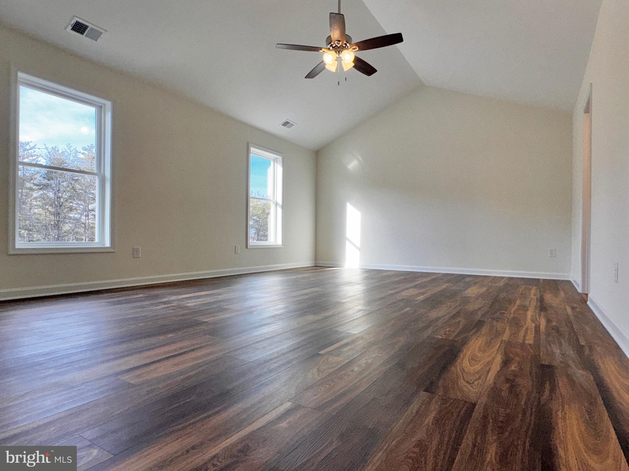 1241 Pine Grove Road Berkeley Springs, WV 25411 - Photo 11 of 19 an empty room with wooden floor chandelier fan and windows