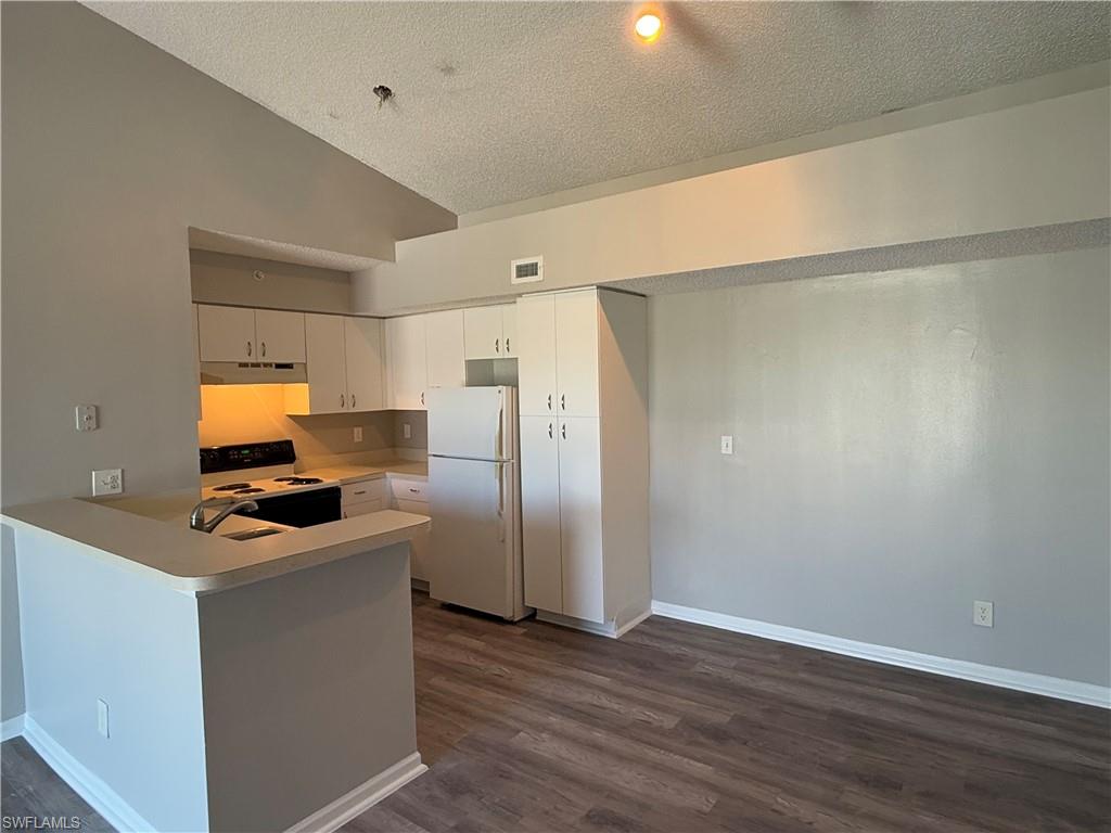 13521 Eagle Ridge Drive, Unit 133 Fort Myers, FL 33912 - Photo 3 of 15 a kitchen with a refrigerator a stove and wooden floor