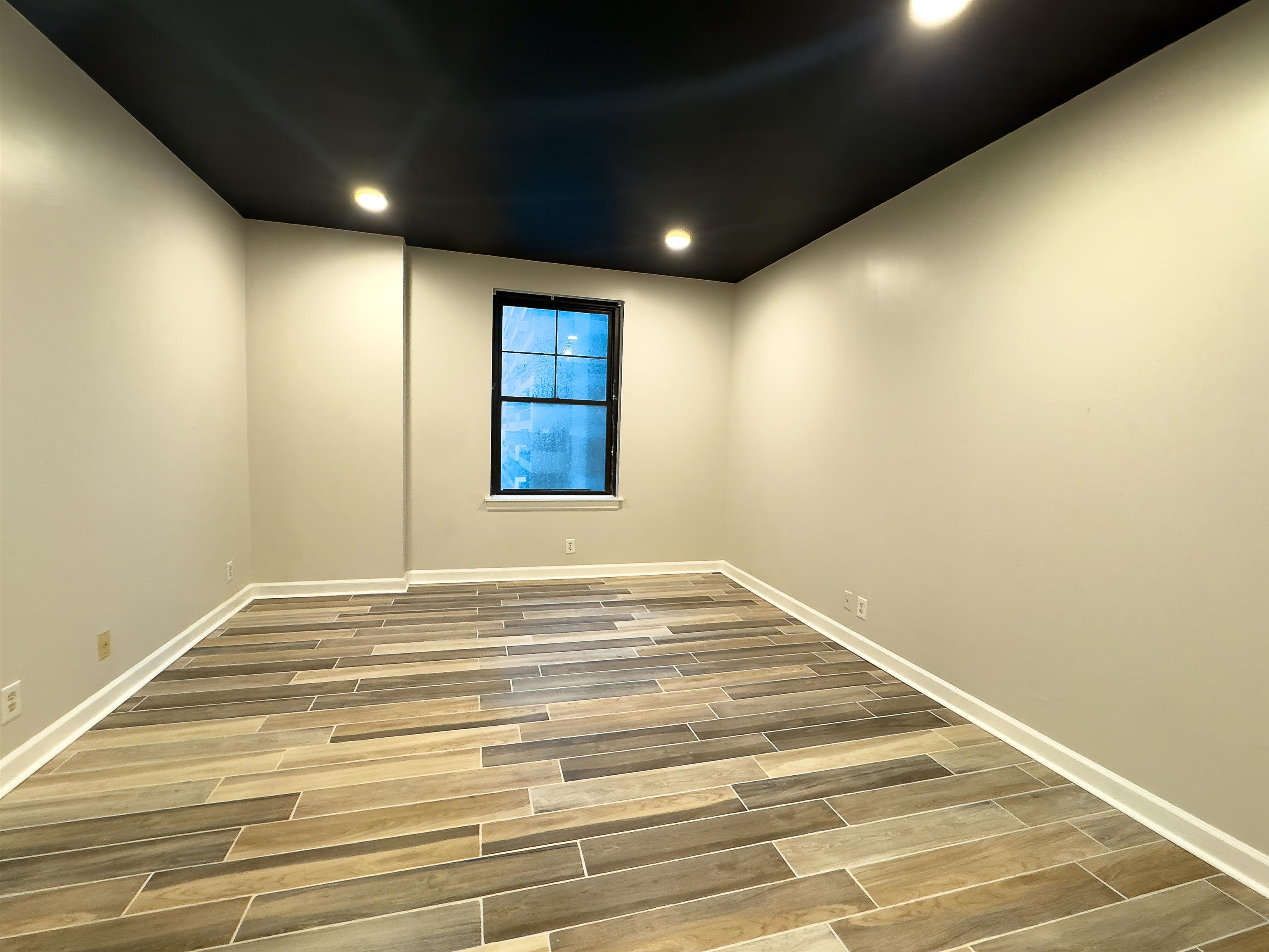 109 North Main Street, Unit 907 Memphis, TN 38103 - Photo 9 of 29 Room featuring plank wood-finish flooring, a dark ceiling with recessed lighting, light-toned walls, and a single window with dark trim