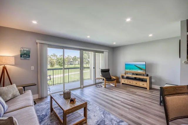 a living room with furniture a rug and a floor to ceiling window