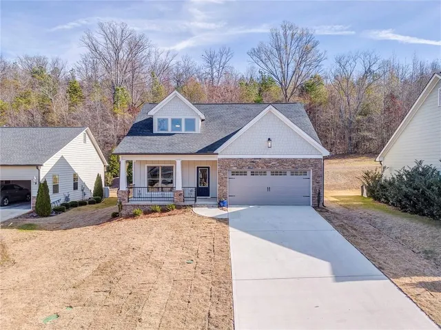 a front view of house with yard outdoor seating and covered with trees