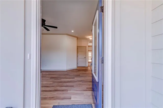 a view of a livingroom with a fireplace a ceiling fan and wooden floor