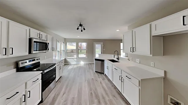 a kitchen with a sink a counter top space stainless steel appliances and cabinets