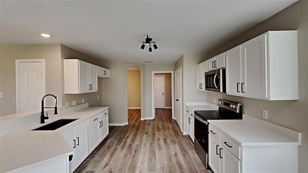 2203 Wagon Wheel Trail Corinth, TX 76208 - Photo 3 of 16 a kitchen with stainless steel appliances a sink stove and cabinets