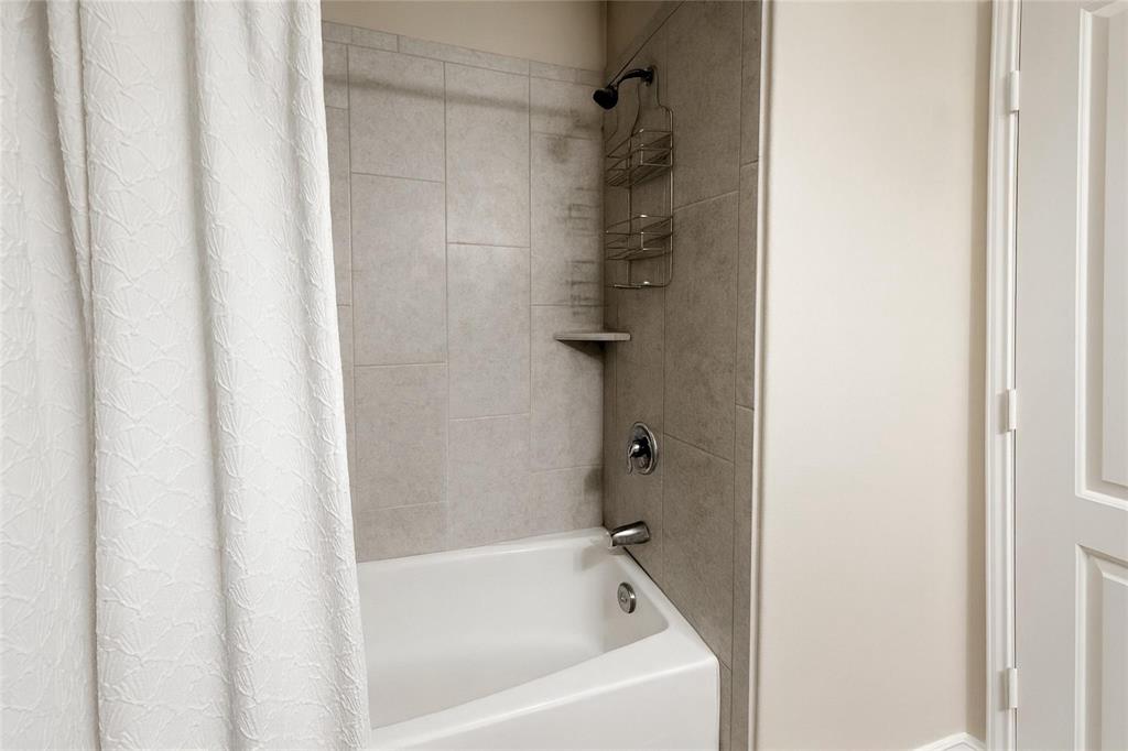 1837 Rialto Lane Crowley, TX 76036 - Photo 11 of 19 Tub and shower combination featuring neutral tile surround, chrome fixtures, and a corner shelf