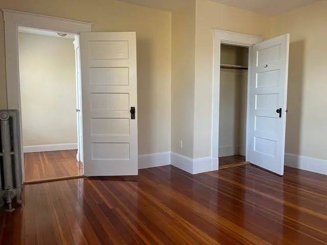 an empty room with wooden floor & cabinet and mirrors