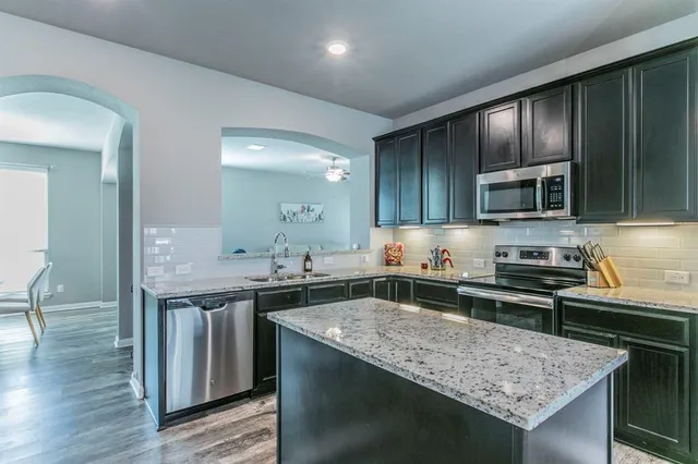 a kitchen with stainless steel appliances granite countertop wooden cabinets a stove top oven a sink and dishwasher